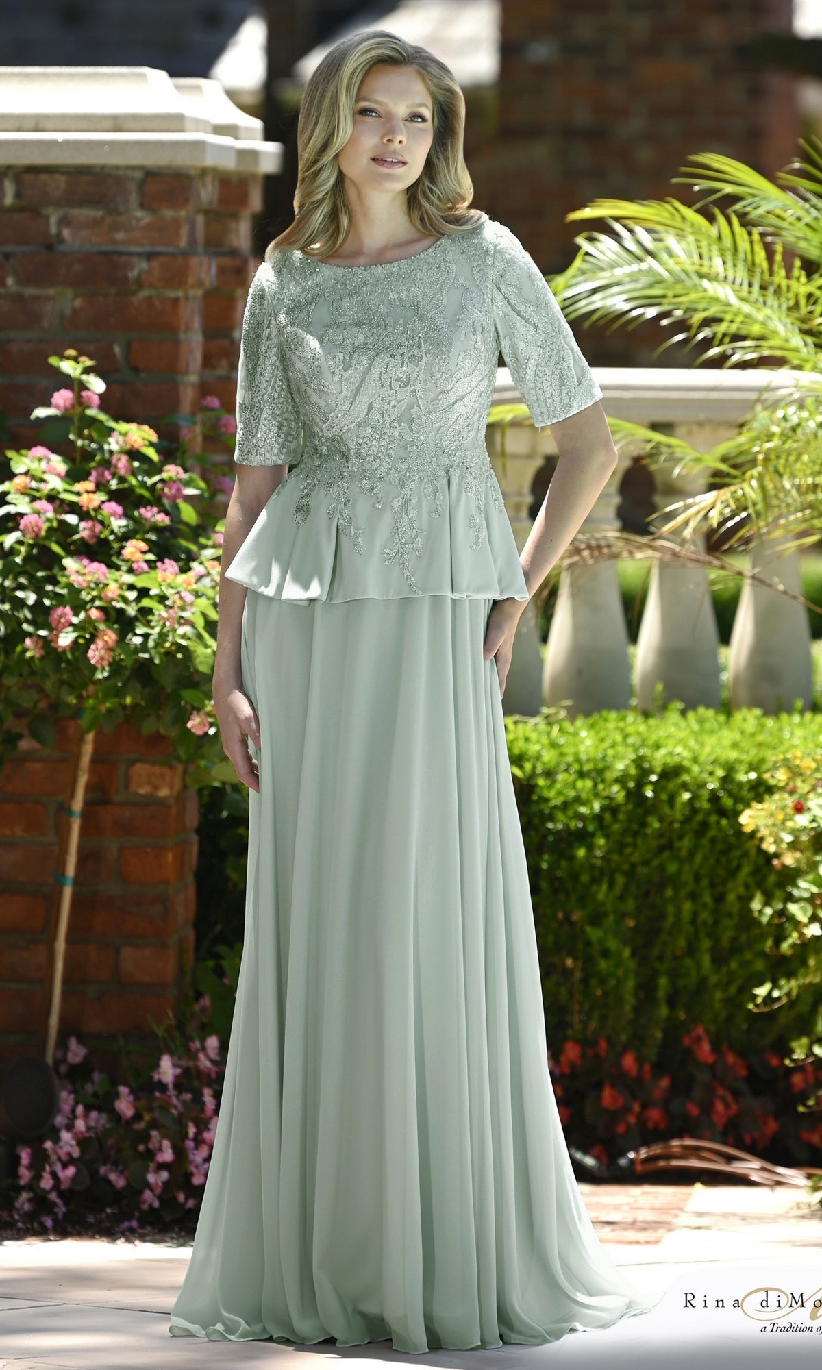 A woman wearing a Beaded Lace Peplum Long Formal Dress: Rina Di Montella RD3642 in seaglass, featuring a floor-length modest evening gown with a beaded lace bodice and a peplum waist.